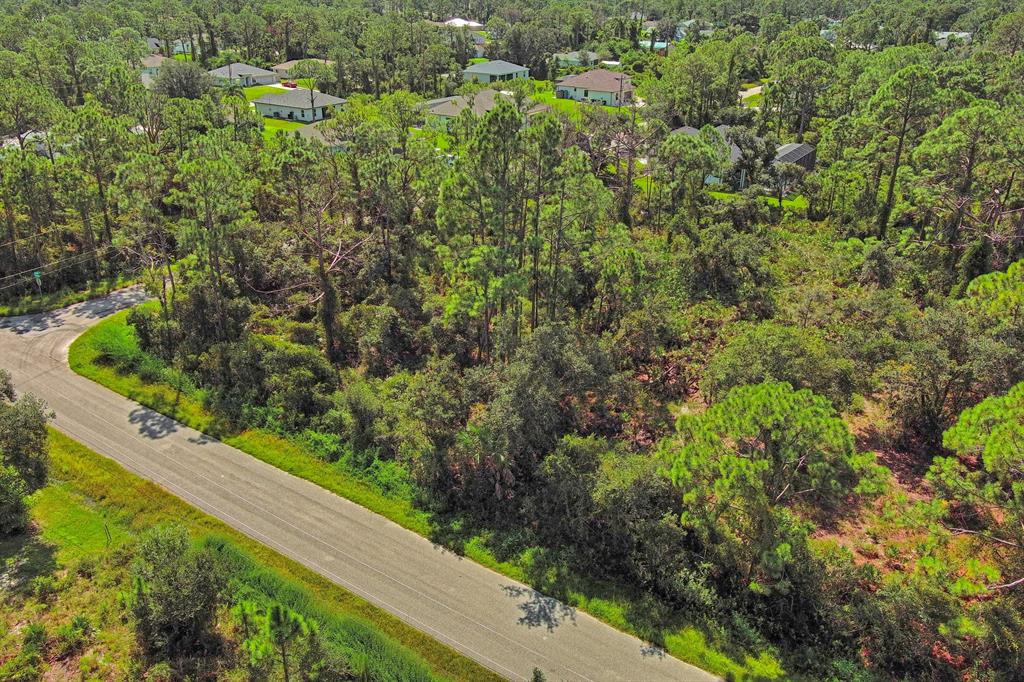 An aerial view shows a wooded, undeveloped residential lot next to a paved road — CASANOVA AVENUE, NORTH PORT, FL