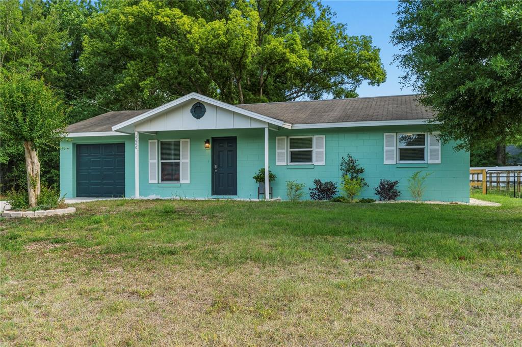 A single-story house with teal concrete block walls, a dark door, and a small garage — 6600 NW 62ND PLACE, OCALA, FL