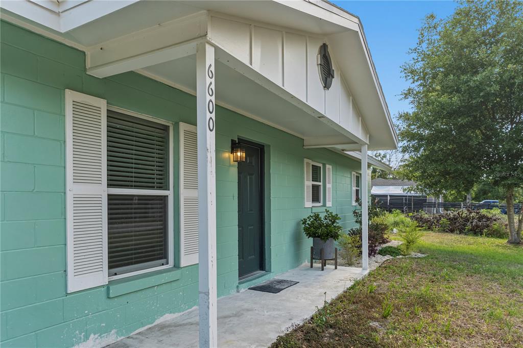 A mint green concrete block house features a covered front porch and white shutters — 6600 NW 62ND PLACE, OCALA, FL