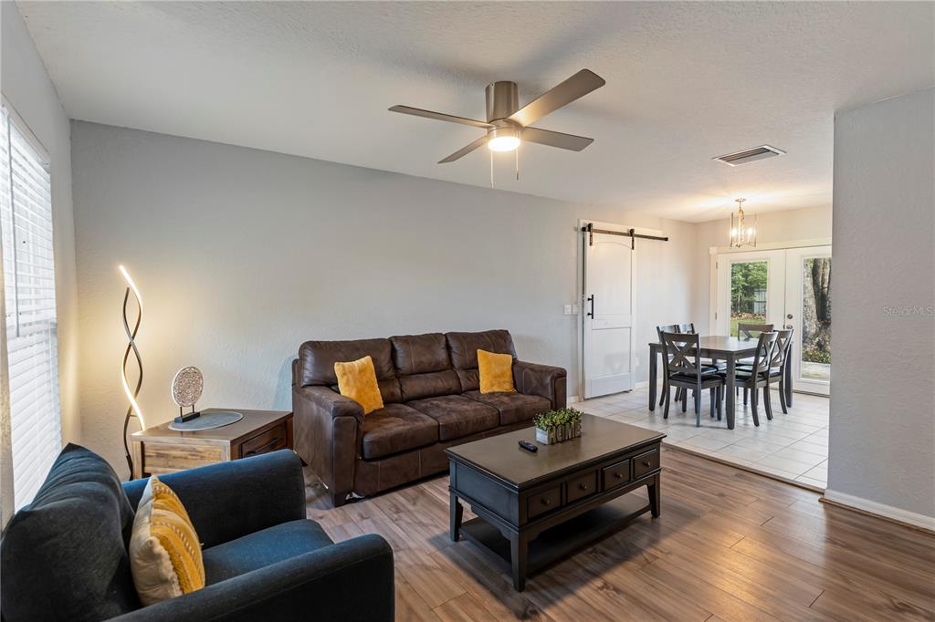 A living room with a brown sofa, blue armchair, coffee table, and adjacent dining area — 6600 NW 62ND PLACE, OCALA, FL