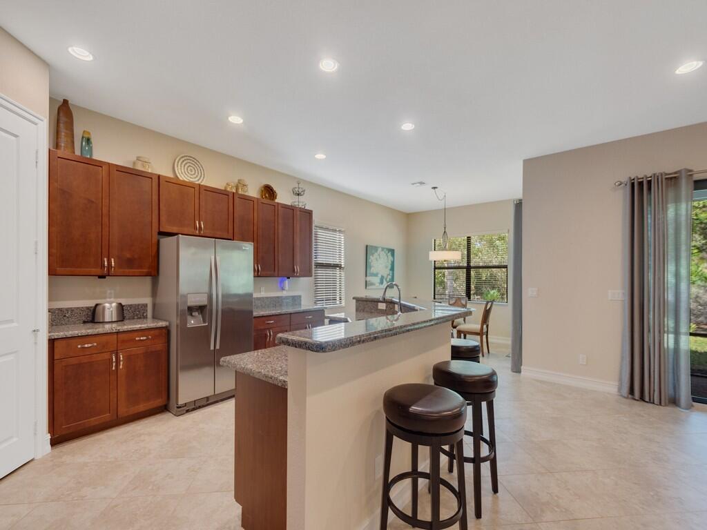 A kitchen with dark wood cabinets, granite countertops, stainless steel appliances, and a breakfast bar — 4338 56th Lane, Vero Beach FL 32967, VERO BEACH, FL