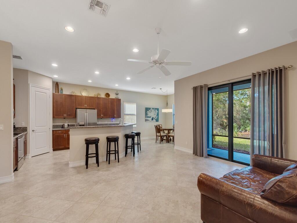 An open-concept kitchen and living area with tile floors, dark wood cabinets, and sliding doors — 4338 56th Lane, Vero Beach FL 32967, VERO BEACH, FL