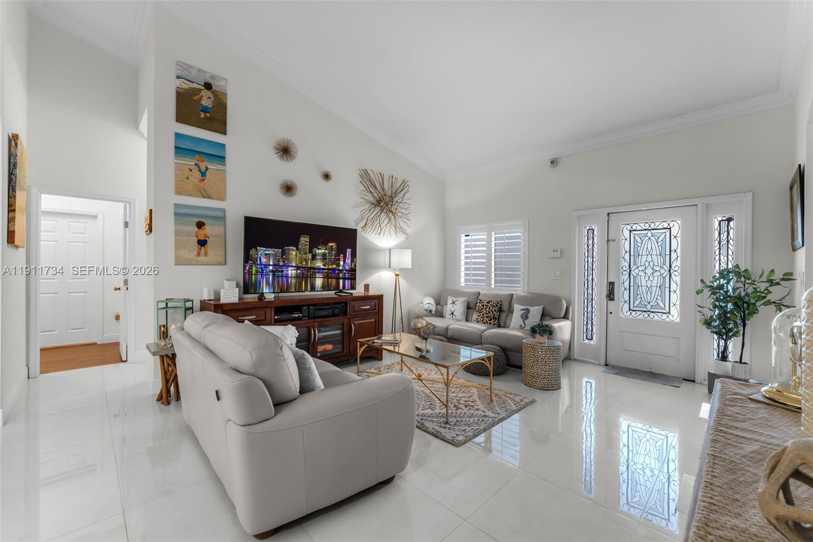 A bright living room features white tile floors, a vaulted ceiling, and a glass-topped coffee table — 12743 SW 220th St, Miami FL 33170, MIAMI, FL