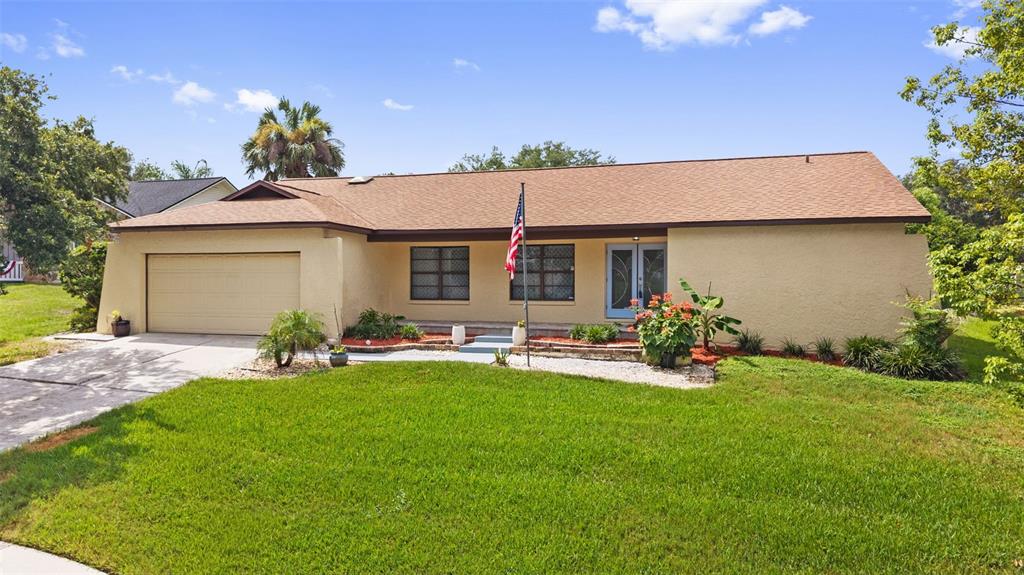 A single-story tan house with a two-car garage, front lawn, and an American flag — 2311 LONG GREEN COURT, VALRICO, FL