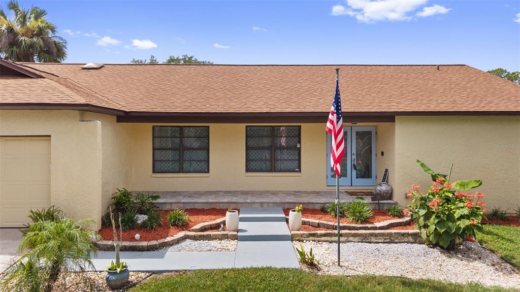 A single-story house with a tan stucco exterior, brown roof, and a front porch — 2311 LONG GREEN COURT, VALRICO, FL