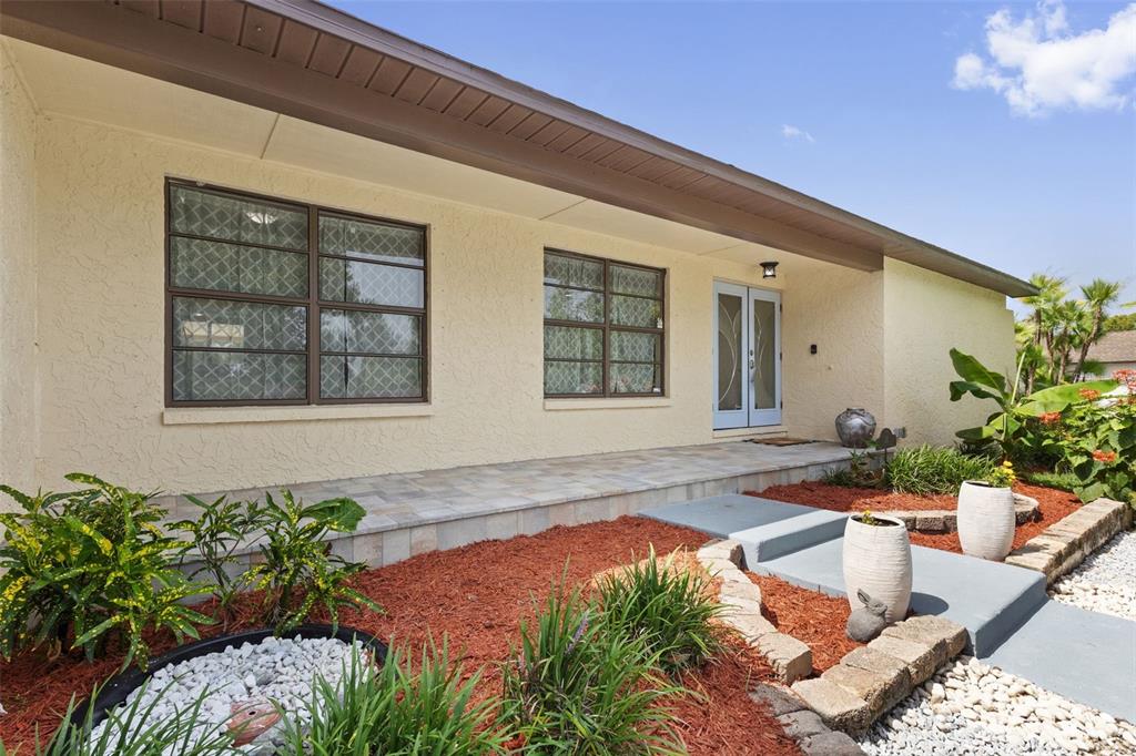 A single-story house exterior features a tiled porch, light stucco walls, and brown-framed windows — 2311 LONG GREEN COURT, VALRICO, FL