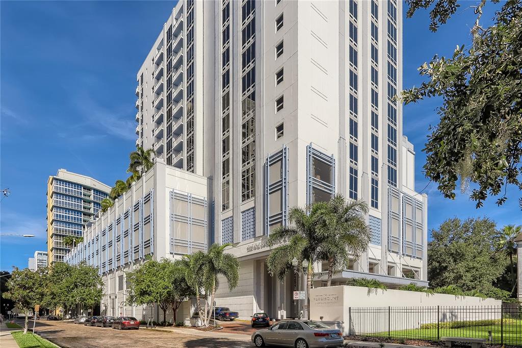 A tall, white multi-story residential building features a parking garage base and palm trees — 415 E PINE STREET, ORLANDO, FL