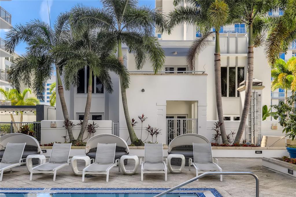 A swimming pool area features lounge chairs and palm trees in front of a white building — 415 E PINE STREET, ORLANDO, FL