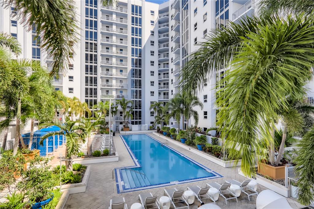 A rectangular swimming pool sits in a courtyard surrounded by a tall white apartment building — 415 E PINE STREET, ORLANDO, FL