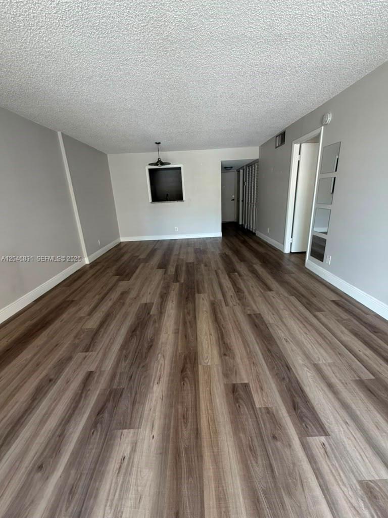 An empty room features wood-look laminate flooring, light gray walls, and a ceiling light fixture — 408 NW 68th Ave # 209, Plantation FL 33317, PLANTATION, FL