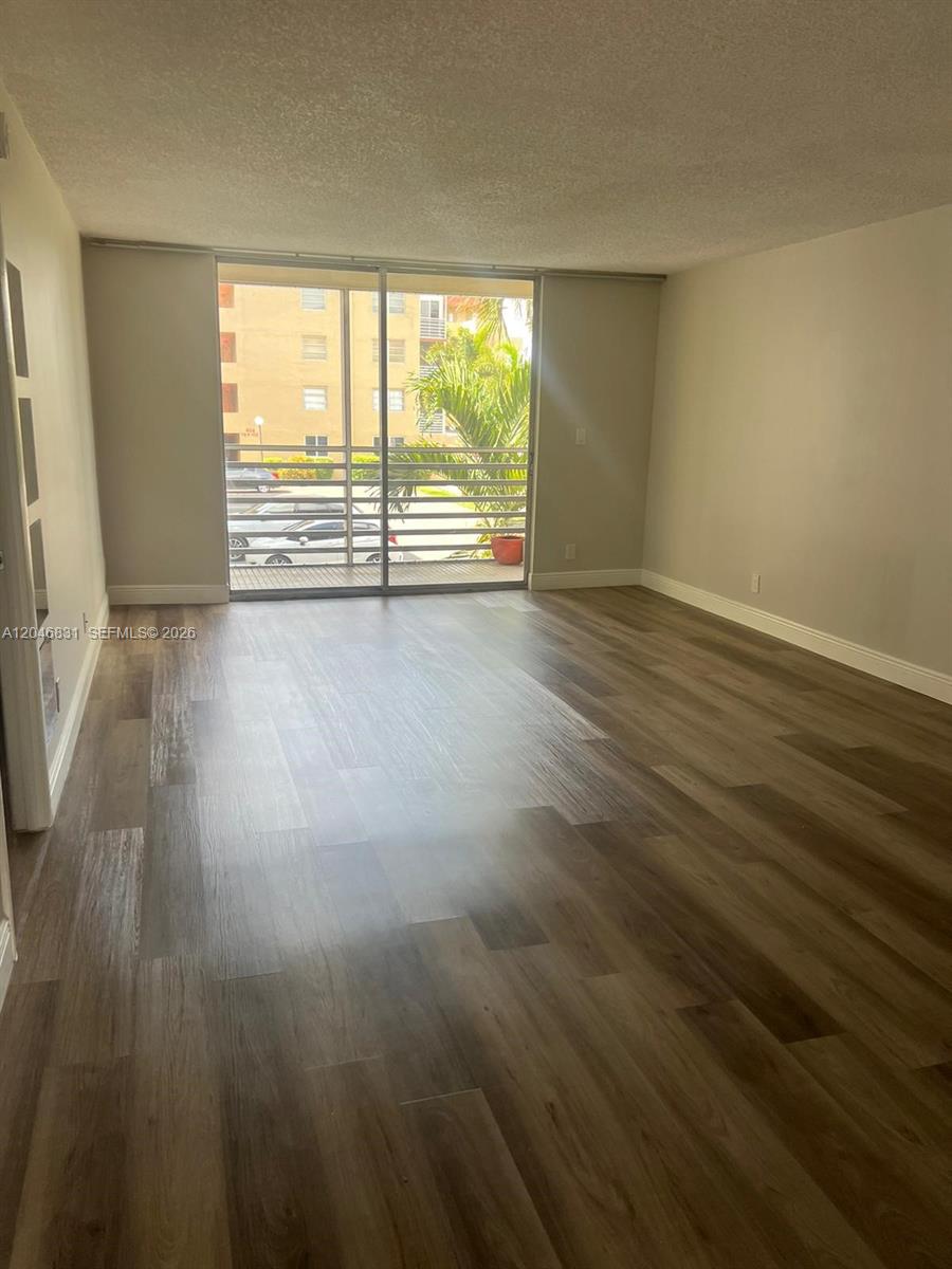 An empty room features wood-look flooring, light-colored walls, and a sliding glass door to a balcony — 408 NW 68th Ave # 209, Plantation FL 33317, PLANTATION, FL