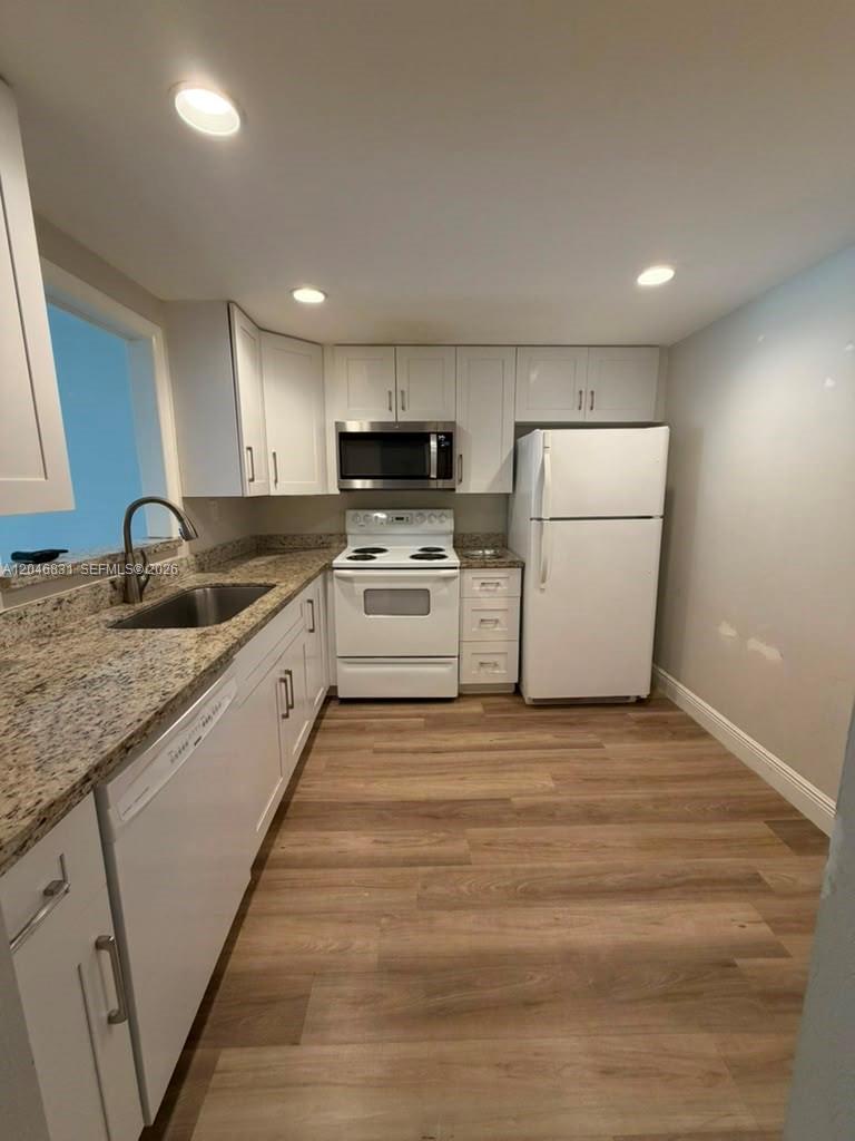 A kitchen features white cabinets, granite countertops, stainless steel appliances, and light wood flooring — 408 NW 68th Ave # 209, Plantation FL 33317, PLANTATION, FL