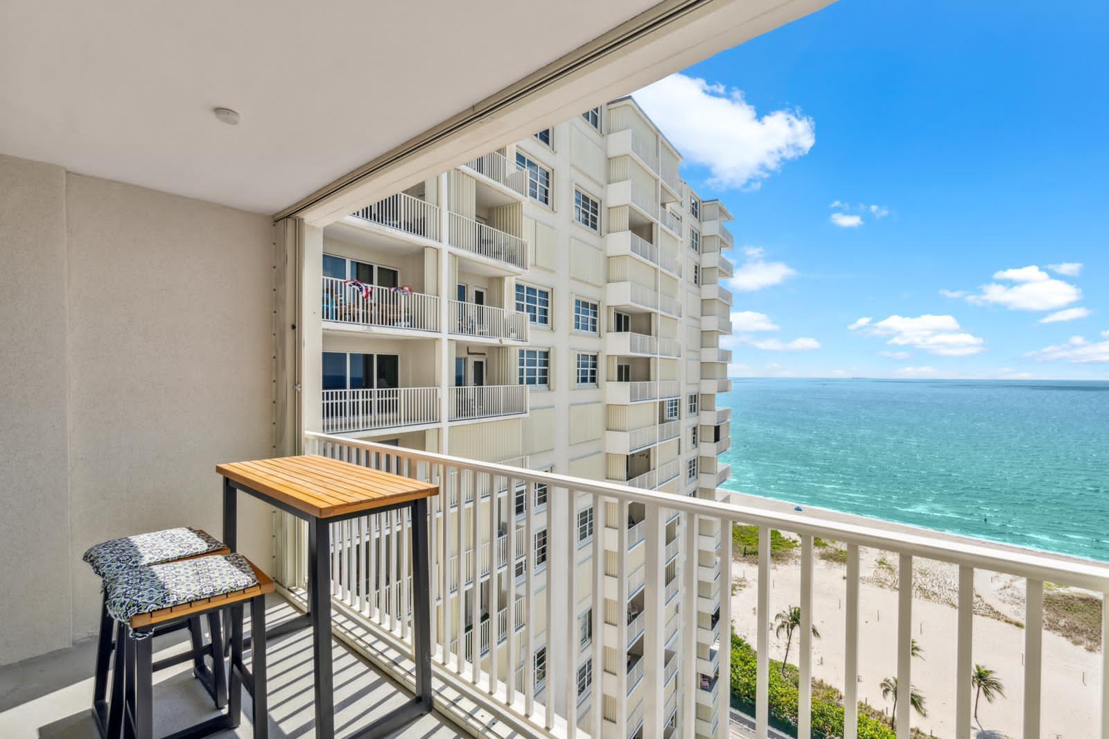 A balcony with a small table and two stools overlooks a beach and ocean — 750 N Ocean Boulevard # 1507, Pompano Beach FL 33062, POMPANO BEACH, FL