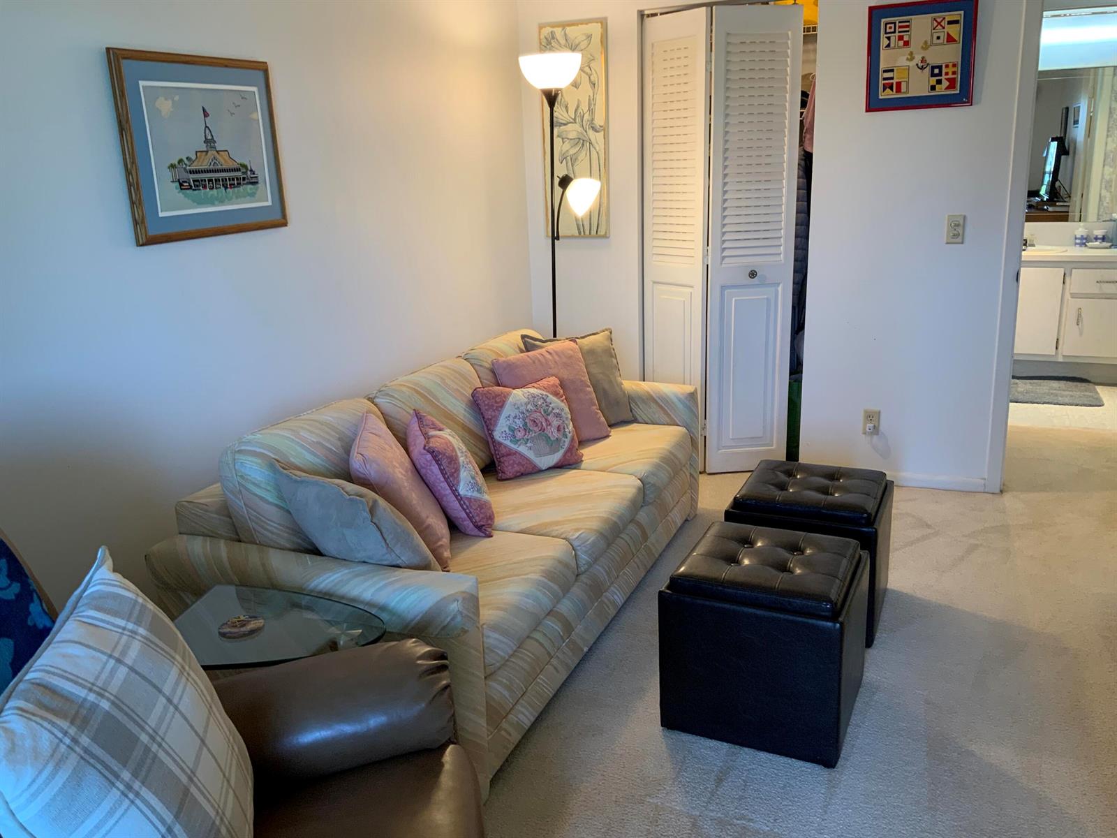A living room features a striped sofa, two black ottomans, and a floor lamp — 2050 Hythe C, Boca Raton FL 33434, BOCA RATON, FL