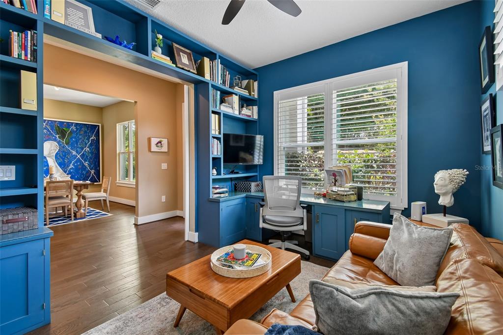 A home office with blue built-in shelving, a desk, a leather sofa, and hardwood floors — 2107 HARGILL DRIVE, ORLANDO, FL