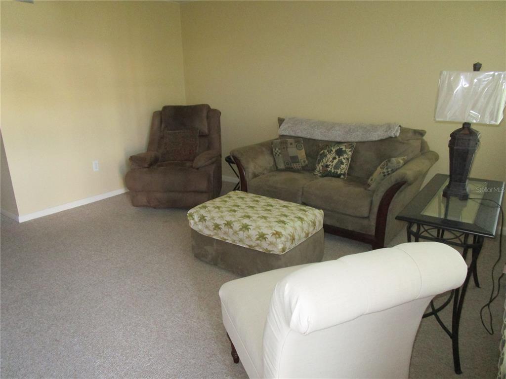 A living room features a brown recliner, a sofa with patterned pillows, and an ottoman — 5876 21ST STREET N UNIT 3, ST PETERSBURG, FL