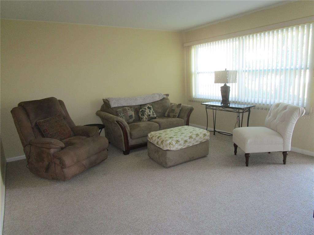 A living room features a brown recliner, a sofa with an ottoman, and a white chair — 5876 21ST STREET N UNIT 3, ST PETERSBURG, FL