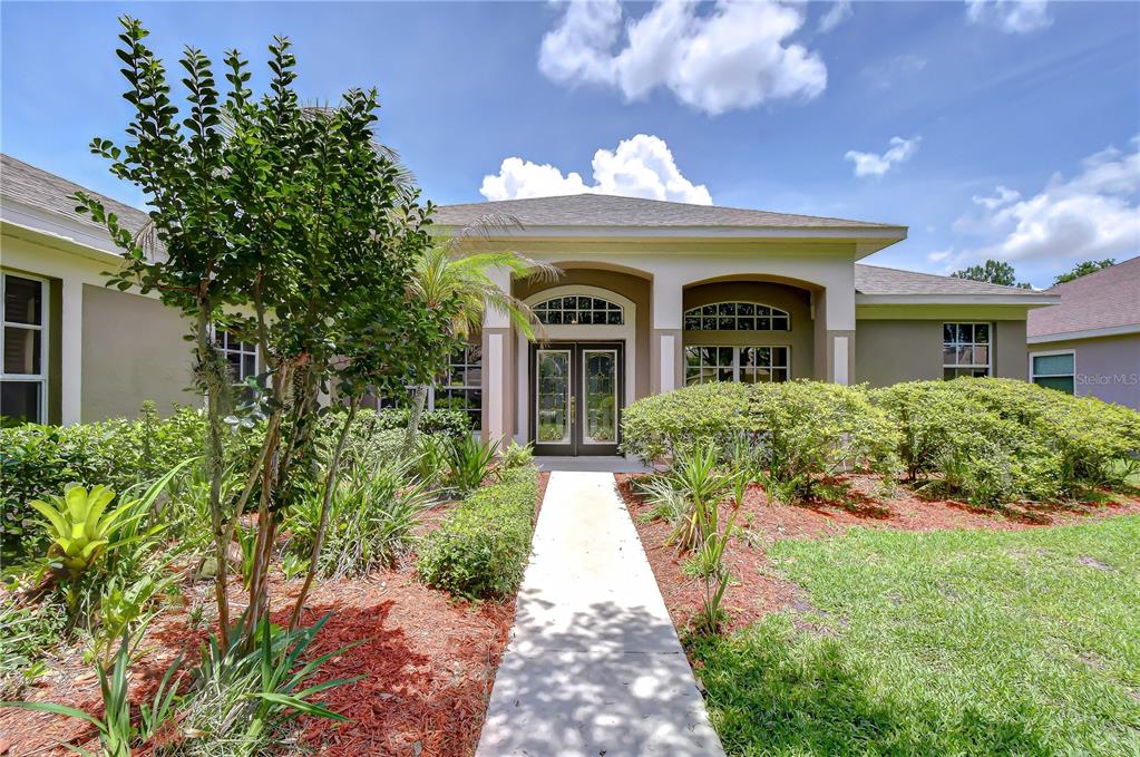 A concrete walkway leads to the front entrance of a single-story house with landscaping — 3512 CORDGRASS DRIVE, VALRICO, FL