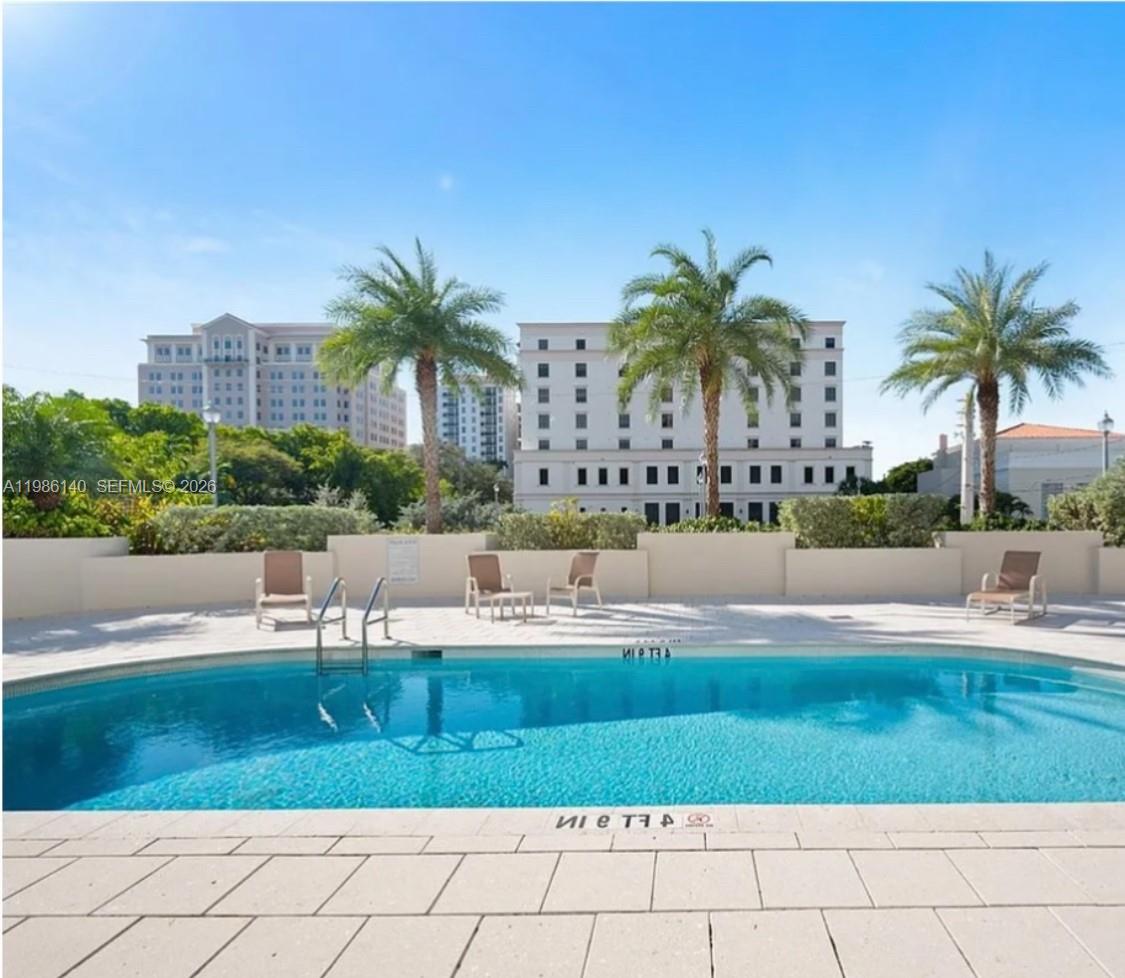 A swimming pool with lounge chairs sits in front of a large multi-story building — 441 Valencia Ave # 803, Coral Gables FL 33134, CORAL GABLES, FL