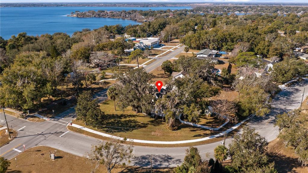 An aerial view shows a house nestled among large trees near a lake — 110 W MINNEHAHA AVENUE, CLERMONT, FL