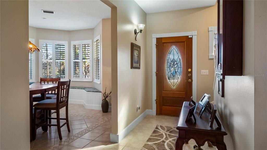 An entryway with a wooden front door leads into a dining area with bay windows — 110 W MINNEHAHA AVENUE, CLERMONT, FL