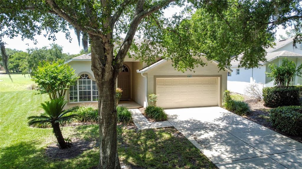 A single-story house with a beige exterior, a two-car garage, and a concrete driveway — 3716 KINGSWOOD COURT, CLERMONT, FL