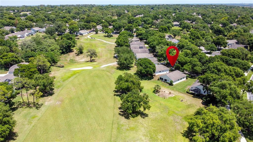 An aerial view shows a house marked with a red pin overlooking a golf course — 3716 KINGSWOOD COURT, CLERMONT, FL