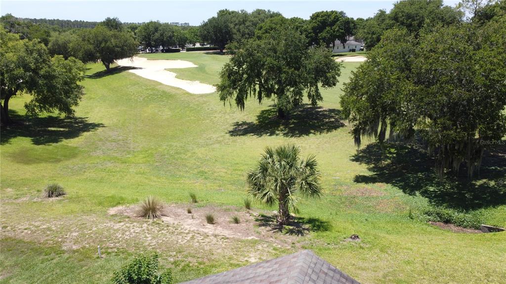 An elevated view of a grassy golf course fairway with sand bunkers and mature trees — 3716 KINGSWOOD COURT, CLERMONT, FL