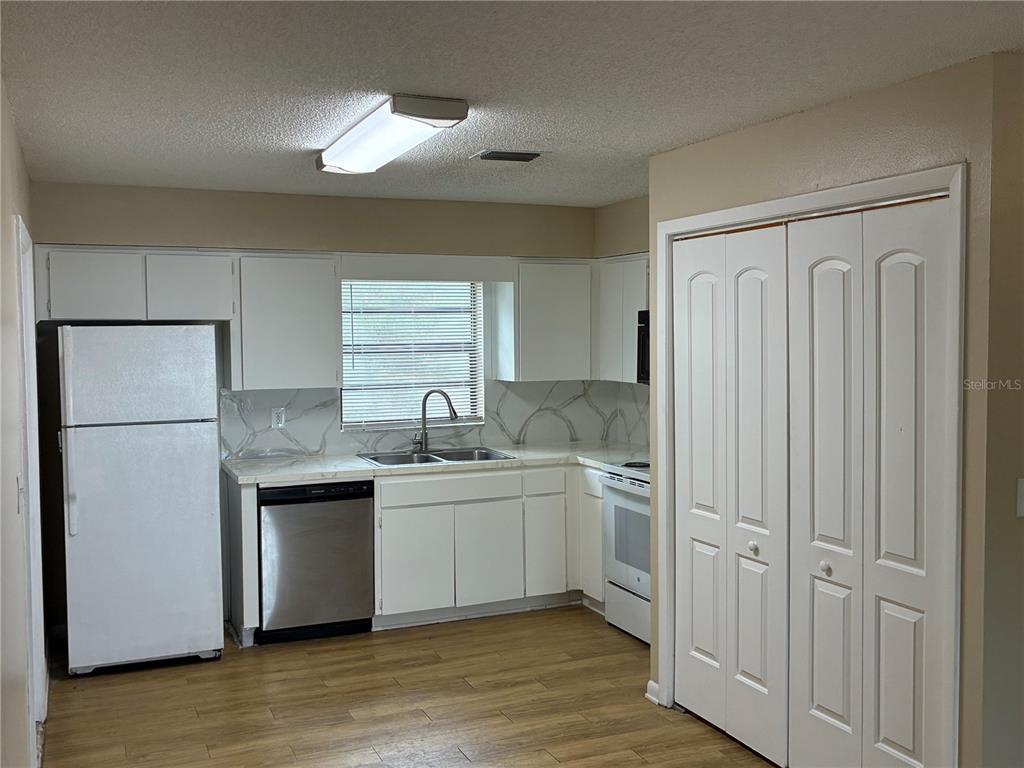 A kitchen with white cabinets, stainless steel appliances, marble-look countertops, and wood-style flooring — 5101 S CLARICE COURT UNIT 1C, TAMPA, FL