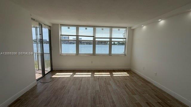 An empty room with wood-look tile flooring, recessed lighting, and a large window overlooking water — 1660 NE 191st St # 1, Miami FL 33179, MIAMI, FL