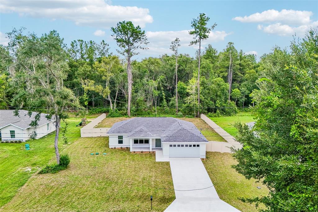 An aerial view shows a single-story white house with a gray roof and concrete driveway — 353 W ERIDANI COURT, CITRUS SPRINGS, FL