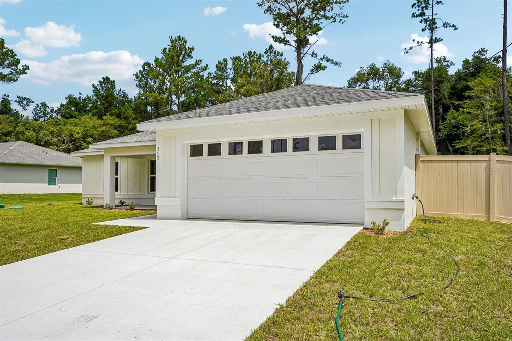 A white single-story house features a two-car garage, a concrete driveway, and a tan fence — 353 W ERIDANI COURT, CITRUS SPRINGS, FL