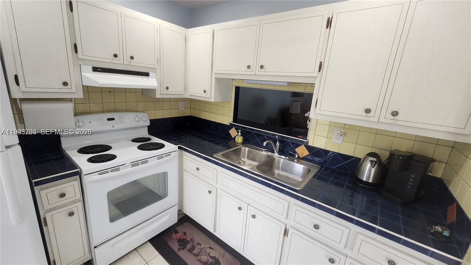 A kitchen features white cabinets, a white stove, and dark blue tiled countertops and backsplash — 4299 NW 16th St # 209, Lauderhill FL 33313, LAUDERHILL, FL