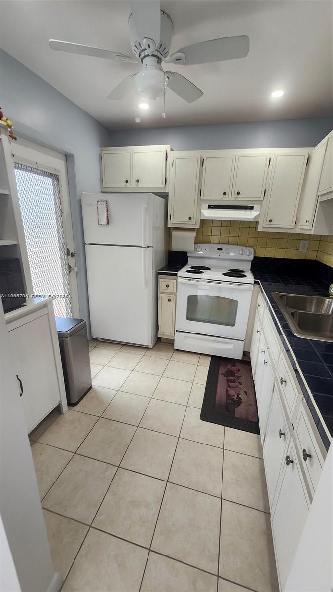 A kitchen features white cabinets, a white refrigerator, a white stove, and blue tile countertops — 4299 NW 16th St # 209, Lauderhill FL 33313, LAUDERHILL, FL