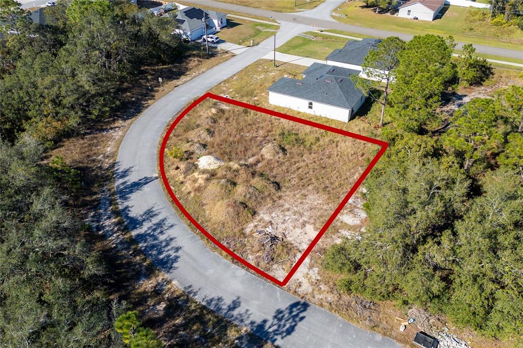 An aerial view shows a vacant, irregularly shaped residential lot outlined in red — 105 TENCH DRIVE, KISSIMMEE, FL