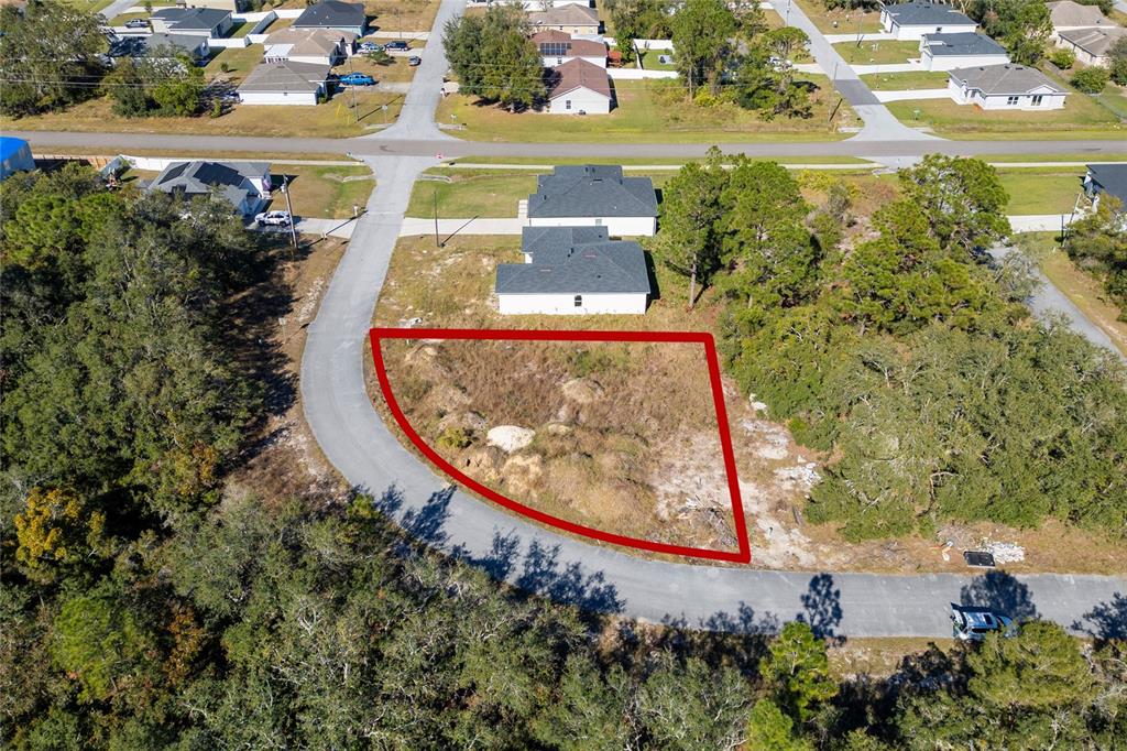 An aerial view shows a vacant, trapezoidal-shaped residential lot outlined in red along a curved road — 105 TENCH DRIVE, KISSIMMEE, FL