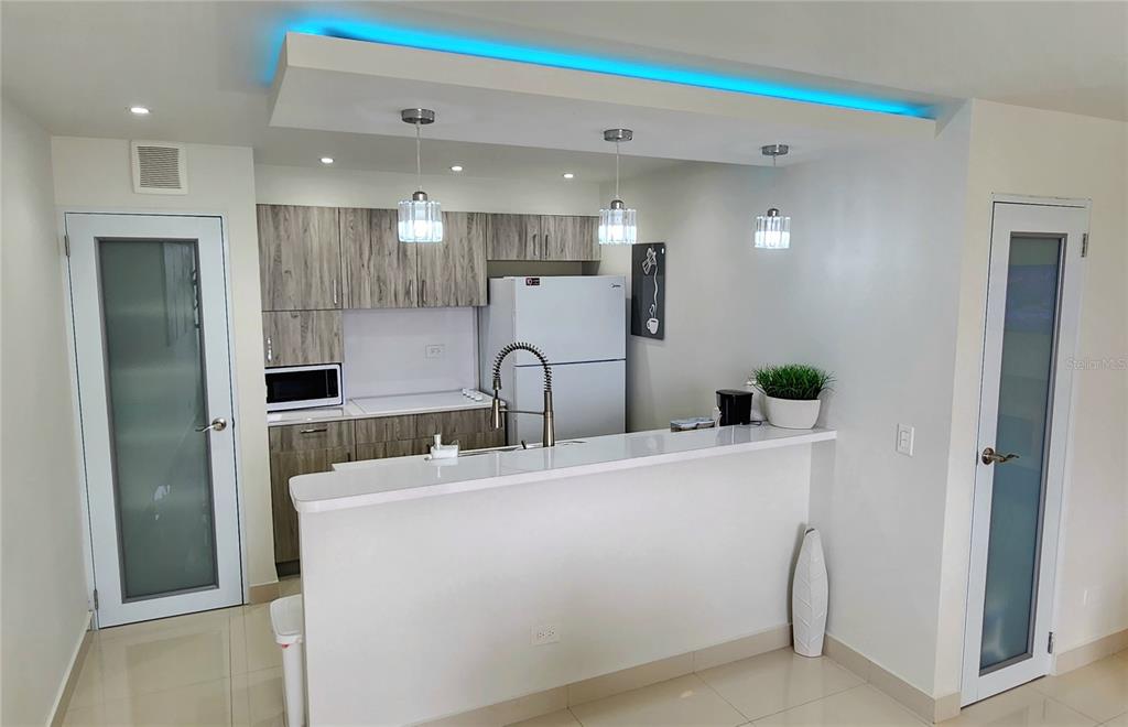 A dining room features a glass table, modern chairs, abstract wall art, and recessed lighting — Esperanza st. SANDY HILLS UNIT 16G, LUQUILLO, PR