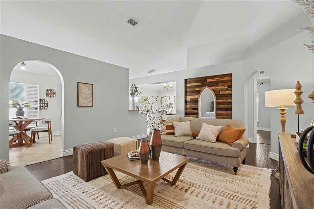 A living room features a wood-paneled accent wall, arched doorways, and a neutral color palette — 2709 SE 45TH AVENUE, OCALA, FL
