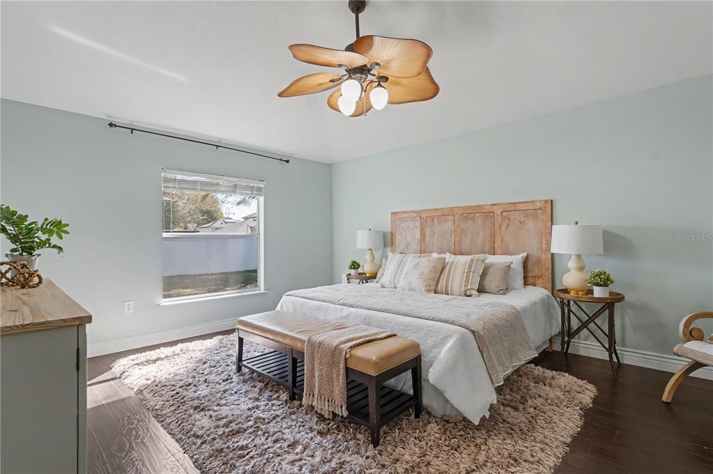 A bedroom features a wooden headboard, a ceiling fan, and a bench on a rug — 2709 SE 45TH AVENUE, OCALA, FL