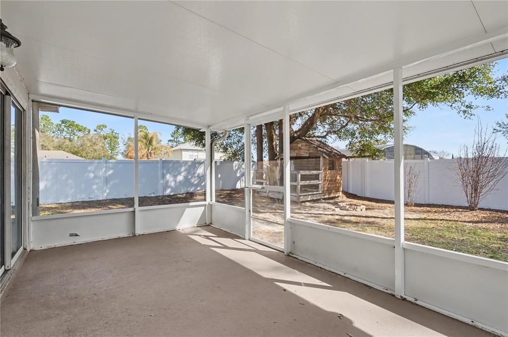 A screened-in patio with a concrete floor overlooks a backyard featuring a wooden playhouse — 2709 SE 45TH AVENUE, OCALA, FL