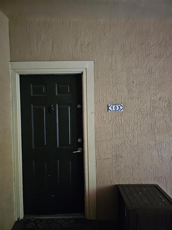 A dark green front door with a door knocker is labeled with the number 103 — 5506 METROWEST BOULEVARD UNIT 13-103, ORLANDO, FL
