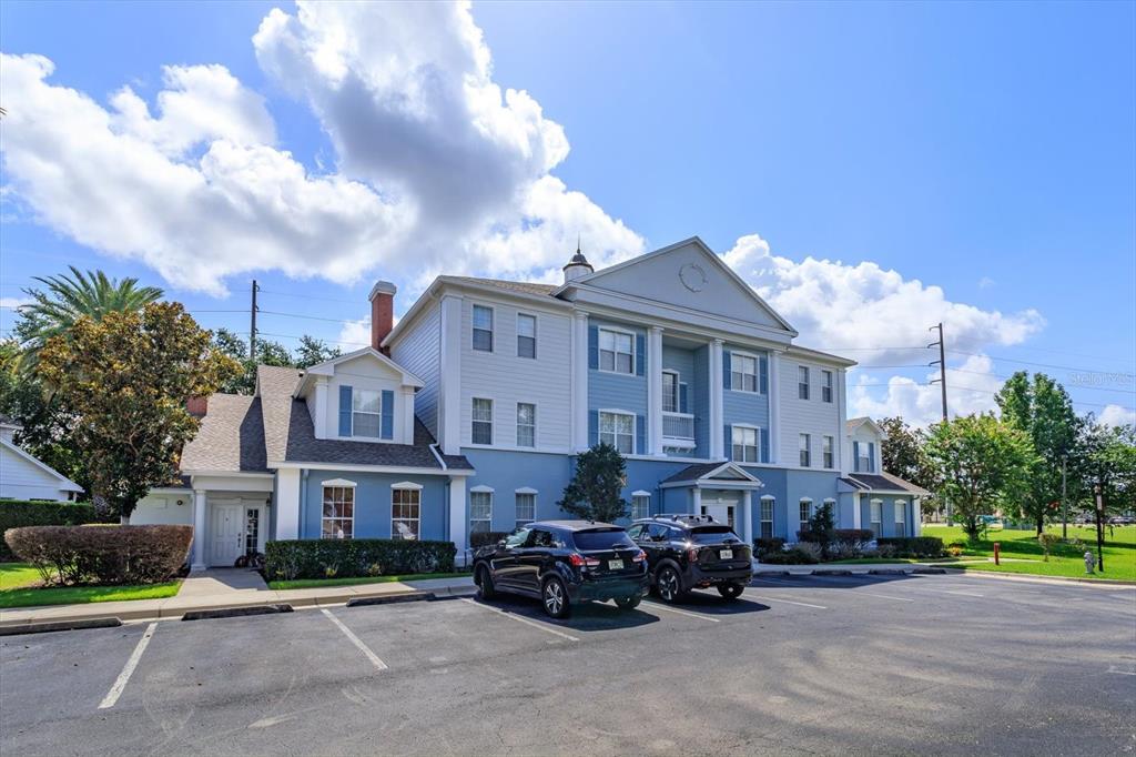 A three-story blue and white building with a parking lot in front — 7644 HERITAGE CROSSING WAY UNIT 102, REUNION, FL