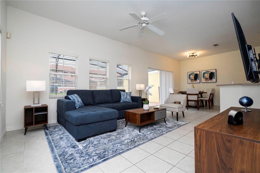A living room features a blue sectional sofa, a wooden coffee table, and a dining area — 3022 WHITE ORCHID ROAD, KISSIMMEE, FL
