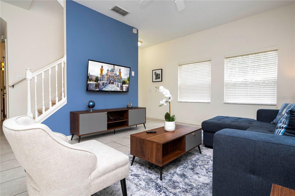 A living room features a blue accent wall, a television, and a dark wood coffee table — 3022 WHITE ORCHID ROAD, KISSIMMEE, FL