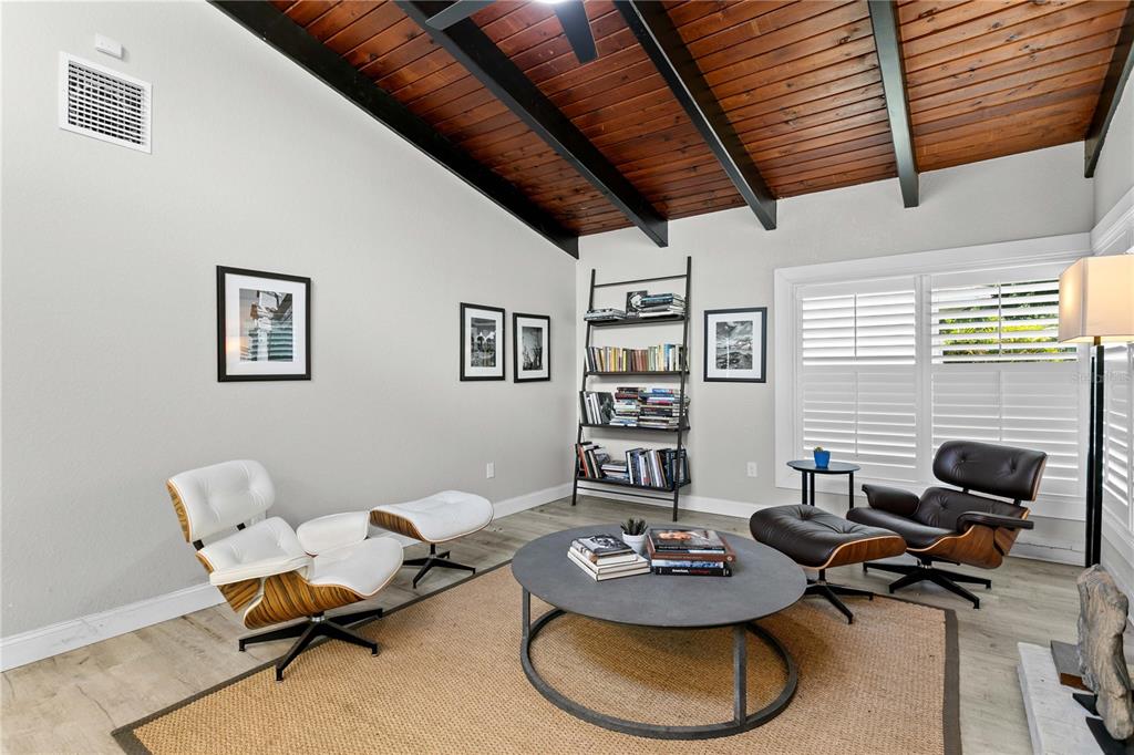 A living room features two Eames-style lounge chairs, a round coffee table, and wood-plank ceilings — 520 LAKE MAGGIORE BOULEVARD S, ST PETERSBURG, FL