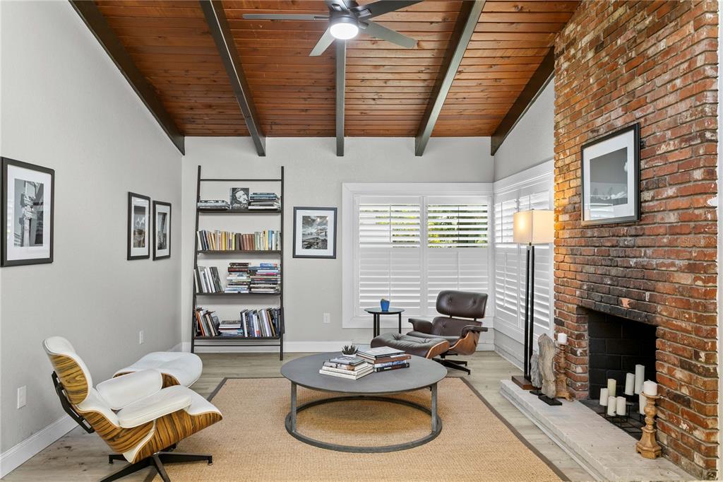 A living room features a brick fireplace, wood-paneled vaulted ceiling, and two lounge chairs — 520 LAKE MAGGIORE BOULEVARD S, ST PETERSBURG, FL