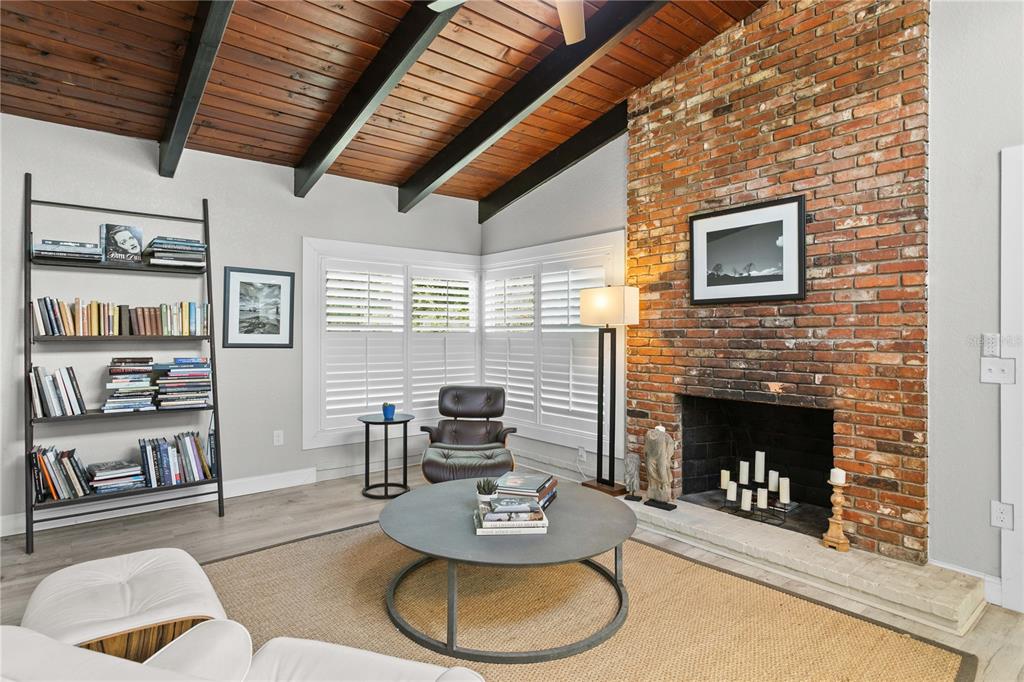 A living room features a brick fireplace, wood-beamed vaulted ceiling, and a bookshelf — 520 LAKE MAGGIORE BOULEVARD S, ST PETERSBURG, FL