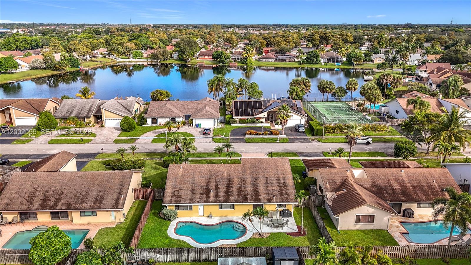 An aerial view shows suburban houses with swimming pools near a lake and tennis court — 8060 NW 51st Ct # 8060, Lauderhill FL 33351, LAUDERHILL, FL