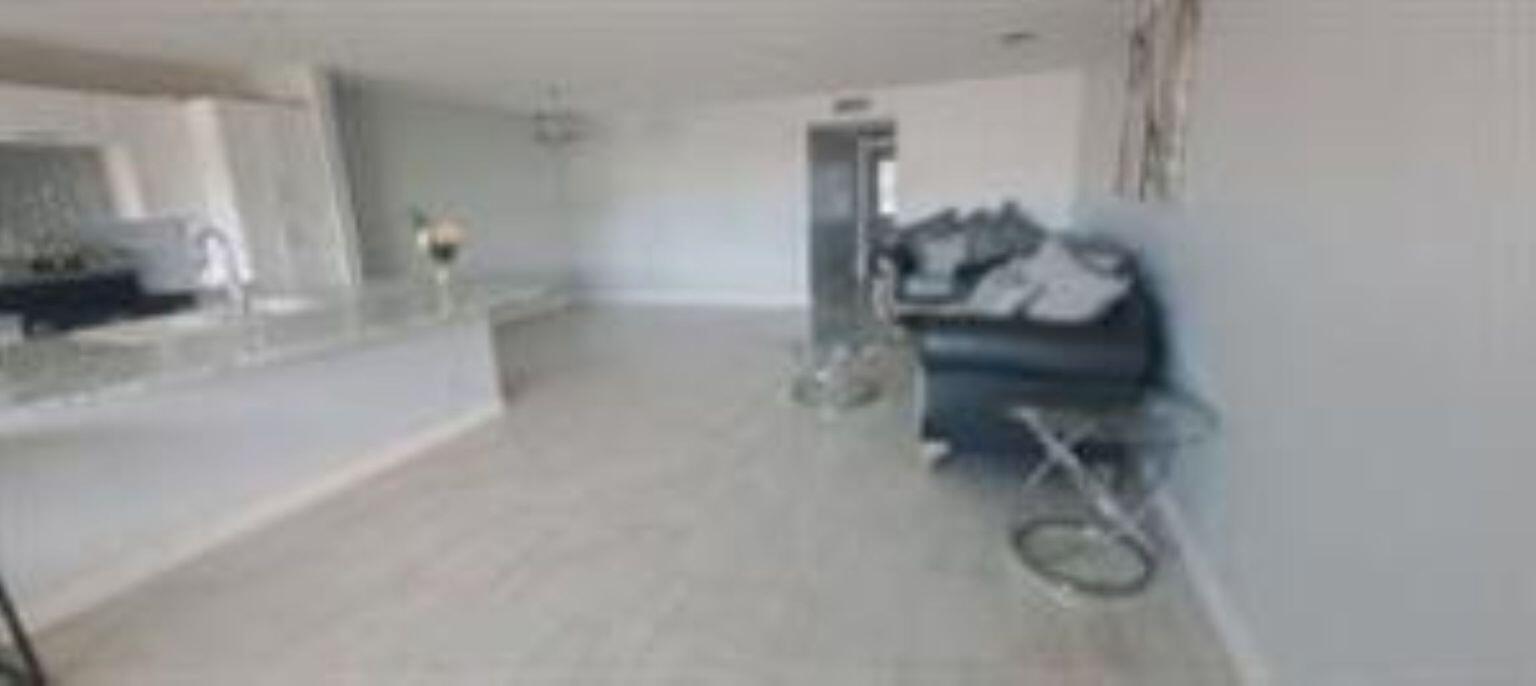 An open-concept living area features light tile flooring, a kitchen island, and dark leather furniture — 14588 Canalview Drive # C, Delray Beach FL 33484, DELRAY BEACH, FL