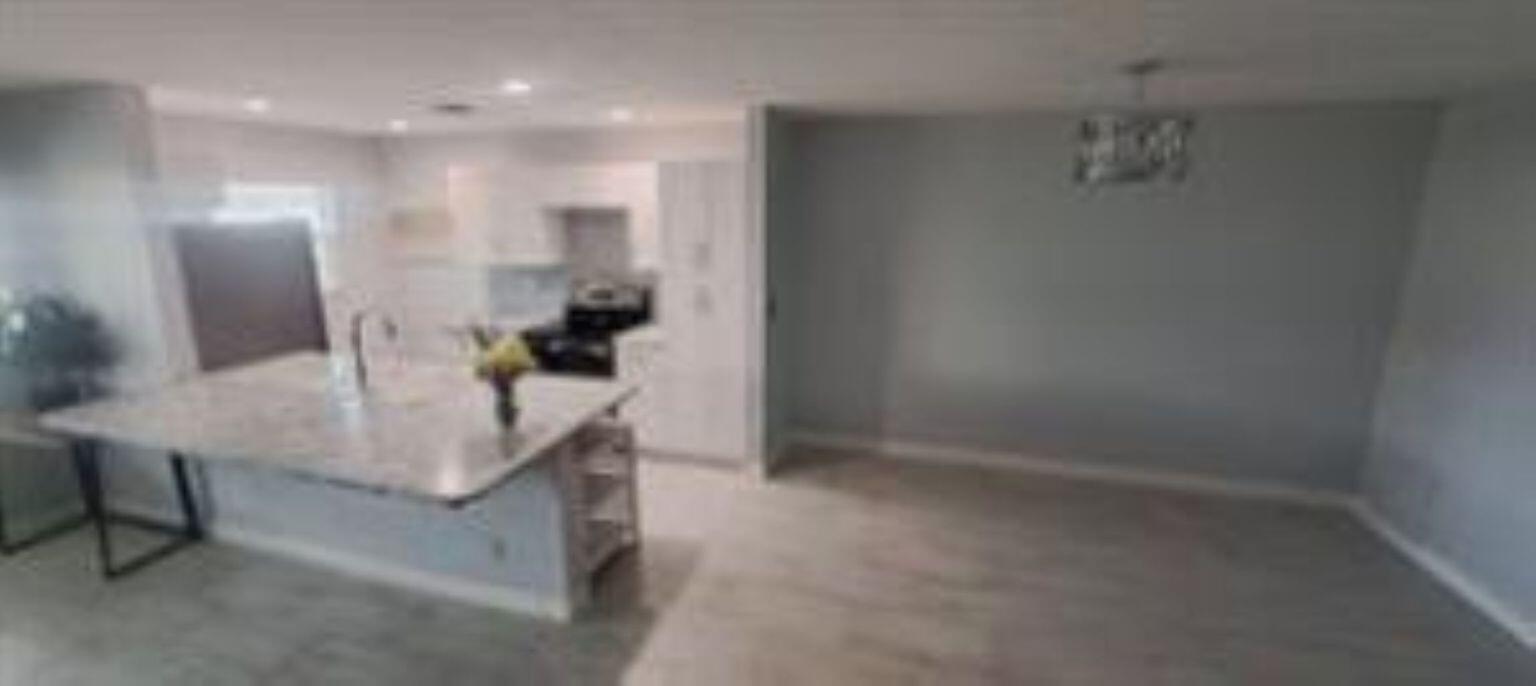 A kitchen with a marble-topped island and white cabinets opens to a dining area — 14588 Canalview Drive # C, Delray Beach FL 33484, DELRAY BEACH, FL